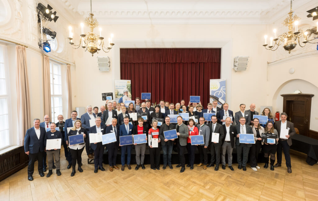 Die Delegationen der zertifizierten und rezertifizierten Mitgliedskommunen sowie neuaufgenommenen Kommunen mit dem Staatsminister für Wohnen, Bau und Verkehr, Christian Bernreiter, dem 1. Vorsitzenden der AGFK, Landrat Robert Niedergesäß, und Christian Heck, Leiter des Referats 67 Radverkehr im StMB. Foto: ©AGFK Bayern/Tobias Hase